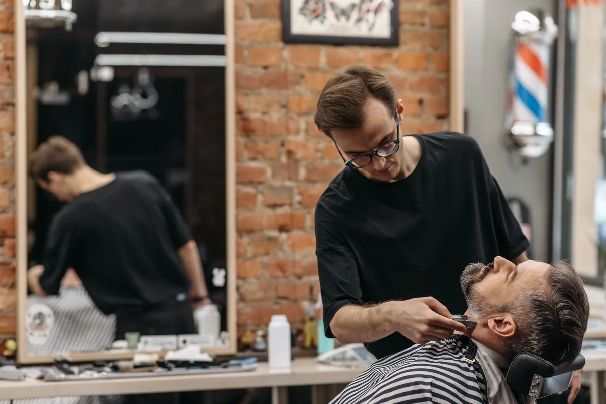 Professional barber carefully trimming a client's beard